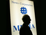 Rupert Murdoch in front of a News Corporation logo