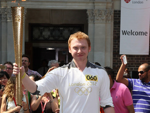 Actor Rupert Grint carries the Olympic Torch during the relay as it visits Middlesex University in London