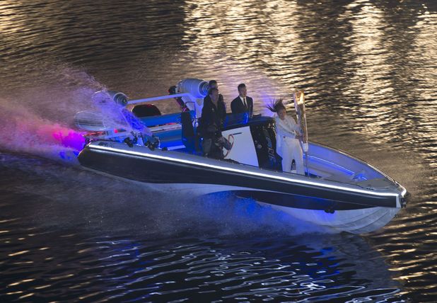 David Beckham arrives by boat with the Olympic Torch.