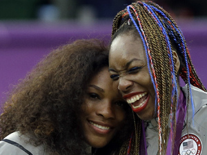 Serena Williams, left, and Venus Williams of the United States laugh together on the podium after receiving their gold medals in women's doubles at the All England Lawn Tennis Club in Wimbledon, London at the 2012 Summer