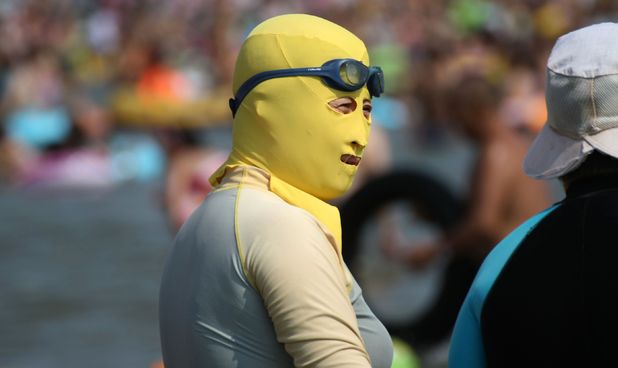 Women wear face masks and full body wetsuits for day at the beach