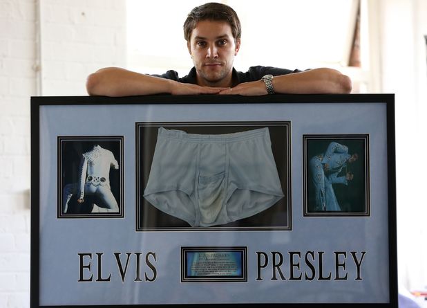 Auctioneer Paul Fairweather with a picture frame containing a pair of unwashed briefs belonging to Elvis Presley, at Omega Auctions in Stockport.