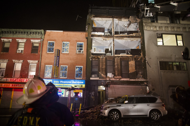 Firefighters look up at the facade of a four-story building on 14th Street and 8th Avenue that collapsed onto the sidewalk Monday, Oct. 29, 2012, in New York.