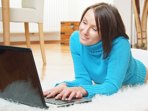Woman on sheepskin rug using laptop