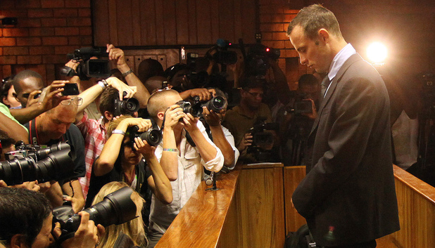 Photographers take photos of Oscar Pistorius as he stands in the dock during his bail hearing 