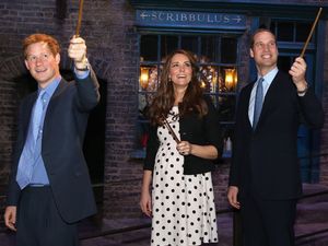 Prince Harry, the Duchess and Duke of Cambridge raise their wands on the set used to depict Diagon Alley in the Harry Potter Films during their visit to Warner Bros studios in Leavesden.