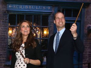 Prince Harry, the Duchess and Duke of Cambridge raise their wands on the set used to depict Diagon Alley in the Harry Potter Films during their visit to Warner Bros studios in Leavesden.