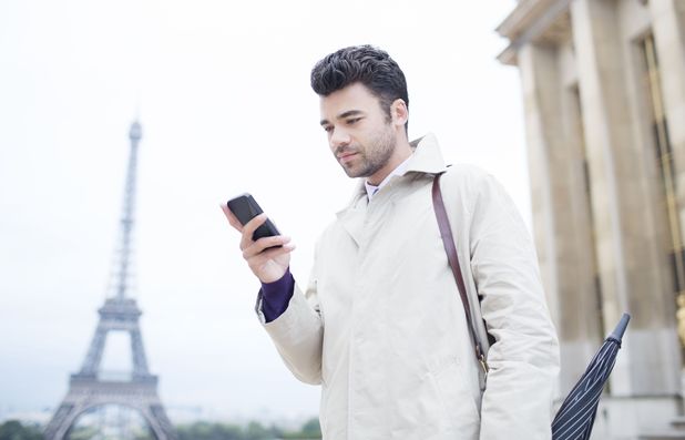 Businessman using phone by Eiffel Tower in Paris