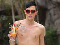 The reality TV star hits the beach in red sock-style swimwear for latest series.