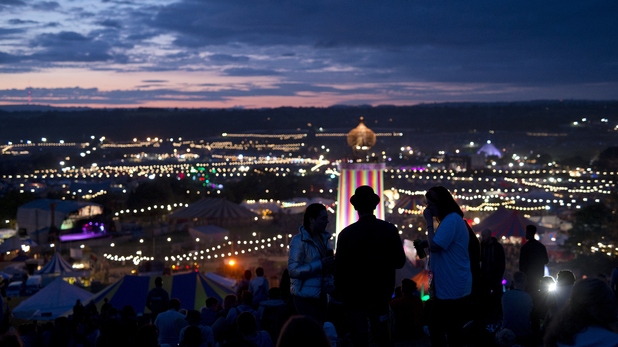 Revellers watch the sun set over the site at the Glastonbury Festival 2015